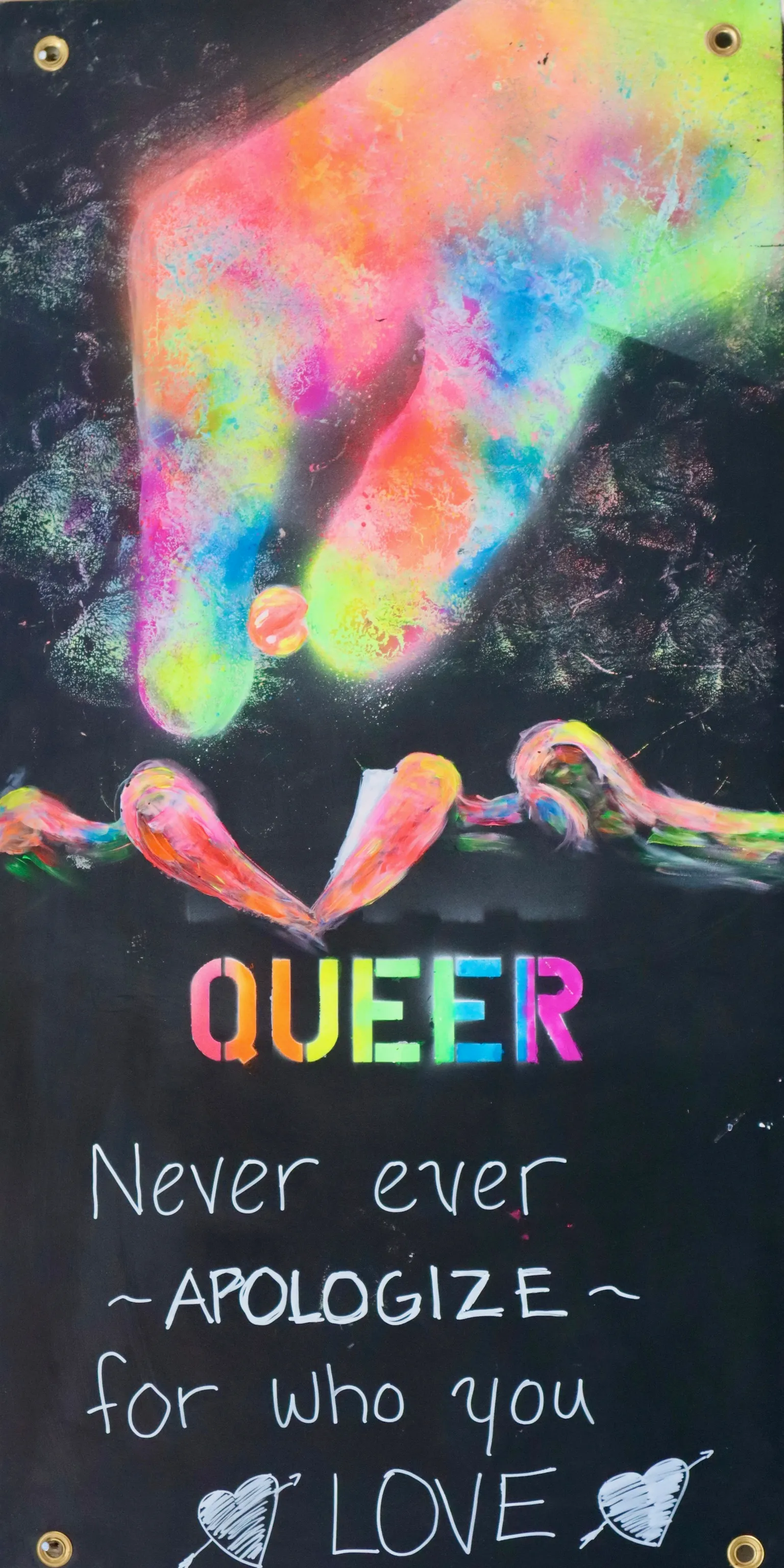 A psychedelic blacklight ASL art panel from Camp ASL Love. A neon rainbow hand points downward from the top of the panel; below it, two hands form a heart. Stenciled rainbow letters read QUEER, with hand-lettered white text: 'Never ever ~APOLOGIZE~ for who you LOVE,' flanked by small heart doodles.
